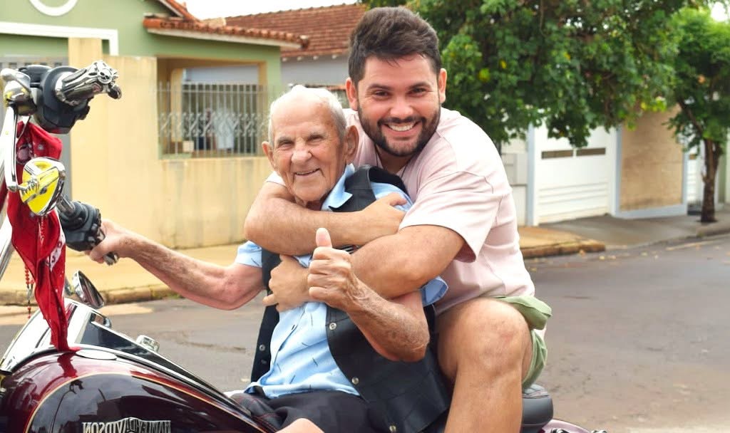 Caio abraçando o Vovô Anésio em cima da moto